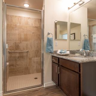 A modern bathroom with a glass-enclosed shower and a vanity featuring a marble countertop.