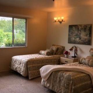 A cozy bedroom with twin beds, warm lighting, and a scenic view through the window.