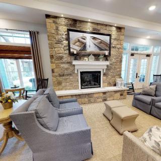 A cozy living room with modern decor, featuring a stone wall fireplace and comfortable seating.