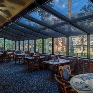 A beautifully lit restaurant with a glass ceiling and large windows offering views of the outdoors.