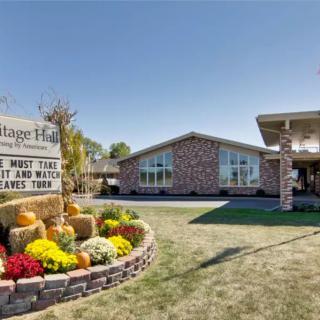 A building with a stone facade, surrounded by a landscaped area featuring autumn flowers and a sign that reads 'Vintage Hills'.