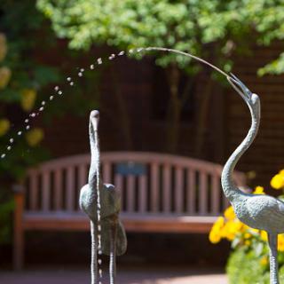A beautiful fountain featuring two crane sculptures gracefully arching water.