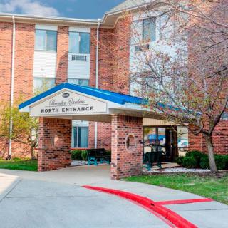 Entrance of a brick hotel building with landscaped surroundings.