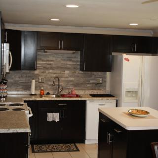 A modern kitchen with dark cabinets, a white refrigerator, and a central island countertop.