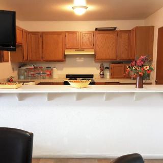 A cozy kitchen with wooden cabinets, a countertop with bar stools, and a vase of flowers.