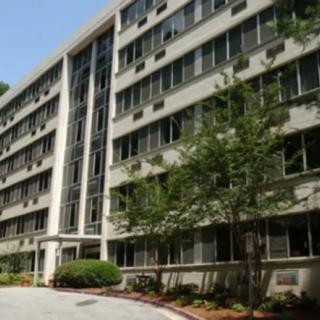A multi-story residential apartment building with trees in front.