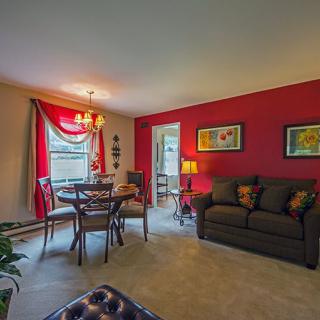 A cozy living and dining area with a bold red accent wall, featuring a comfortable sofa and a charming dining table setup.