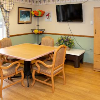 A cozy dining area featuring a wooden table, chairs, and a television.