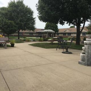 A tranquil courtyard with benches and a fountain, surrounded by trees and landscaping.