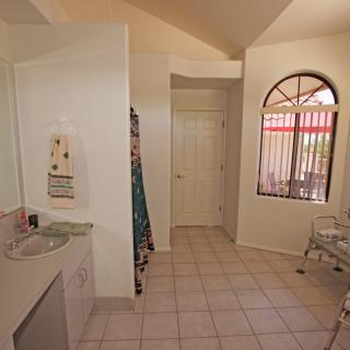 A bright bathroom with a tile floor and arched window.