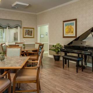A cozy dining area featuring a piano, artwork, and wooden furniture.