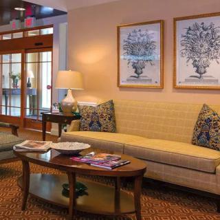 A cozy living room with a sofa, coffee table, lamp, and decorative artwork on the wall.