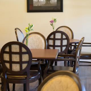 A cozy dining area with neatly arranged tables and chairs, each adorned with a small vase of flowers.