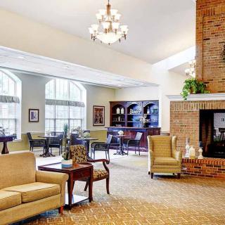 A spacious and elegantly furnished living room featuring a chandelier, fireplace, sofa, and bookshelf.