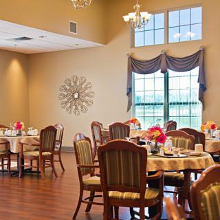 An elegant dining room with neatly arranged tables and chairs, complemented by decorative elements and large windows.