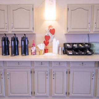A well-organized coffee station with beverage dispensers and heart-themed decorations on a counter.