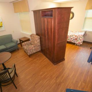 A cozy living space featuring a wooden partition, seating area, and a bed.