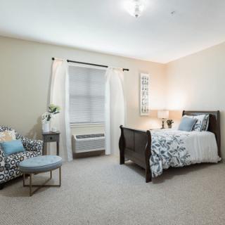 A cozy bedroom with a comfortable bed, stylish chair, and soft lighting.
