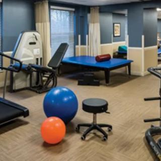 A fitness room equipped with various exercise machines and therapy balls.