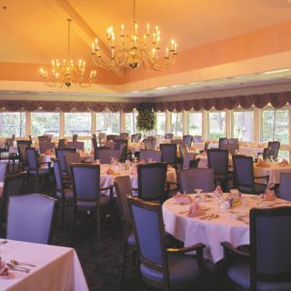 An elegant dining room with chandeliers and neatly arranged tables and chairs.