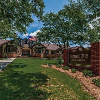 Entrance to a residential complex with a large sign and landscaping.