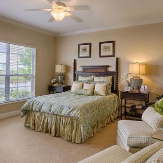 A cozy bedroom with elegant decor, featuring a comfortable bed, lamps, and a window view.