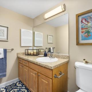 A neatly arranged bathroom with a wooden vanity, large mirror, and modern decor.