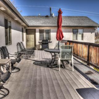 A cozy outdoor deck area with seating, a table, and an umbrella for shade.