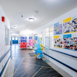 A bright hospital hallway decorated with colorful balloons and informative posters.