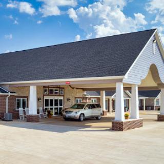A welcoming hotel entrance with a spacious driveway and clear blue skies.