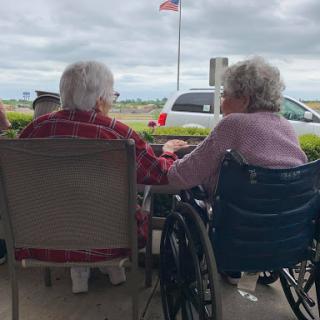 Two elderly friends enjoying each other's company outdoors, sharing a moment of connection.