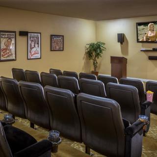An empty home theater with rows of chairs and a projector screen.