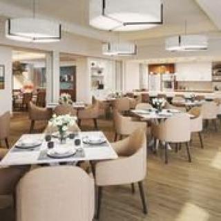A modern dining area with elegantly arranged tables and chairs, featuring stylish lighting and decor.