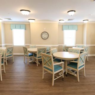 A neatly arranged dining room with round tables and comfortable chairs.