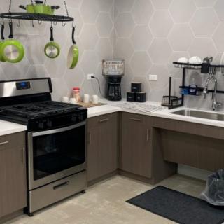 A modern kitchen with a stove, sink, and hanging green cookware.