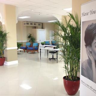 A quiet waiting area with seating, potted plants, and a large poster in the corridor.