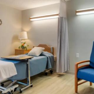 A clean and well-lit hospital room with a bed and chair.