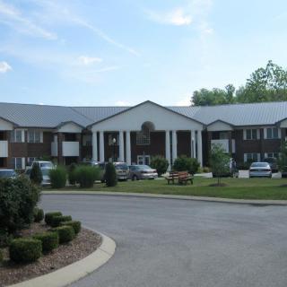 A residential apartment complex with a parking lot and landscaped surroundings.