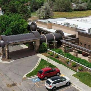 Aerial view of a building with an adjacent parking lot and surrounding greenery.