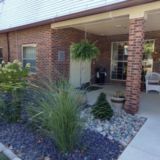 A welcoming porch with neatly arranged landscaping and vibrant plants.