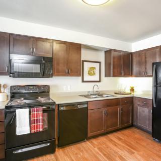 A modern kitchen with dark wood cabinets and black appliances.