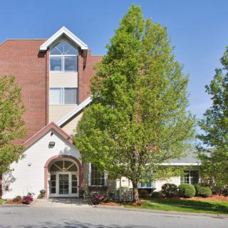 A view of a multi-story building with an entrance surrounded by trees.