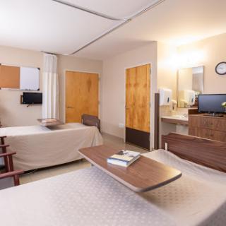 A well-lit hospital room featuring two beds, designed for patient comfort and care.