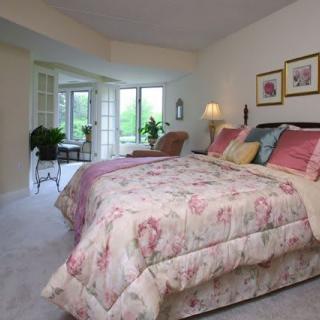 A cozy bedroom with a floral bedspread, abundant natural light, and tasteful decor.