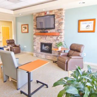 A cozy living room featuring armchairs, a fireplace, and a television mounted on the wall.
