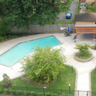 An aerial view of an outdoor swimming pool surrounded by greenery and walkways.