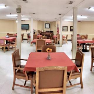 A dining room with multiple tables covered in red tablecloths, arranged for communal use.