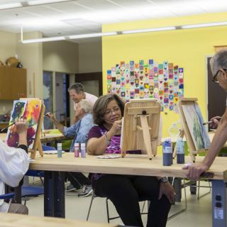 A group of people engaged in painting during an art class, each working at individual easels.