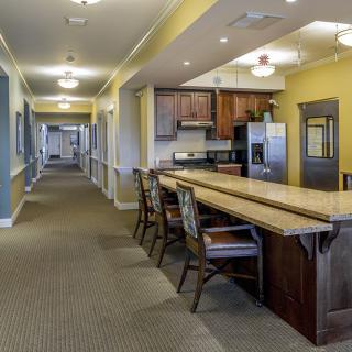 A modern interior hallway with a kitchen area featuring a large countertop and chairs.