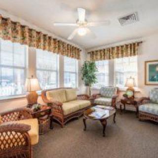 A cozy living room with wicker furniture and large windows.